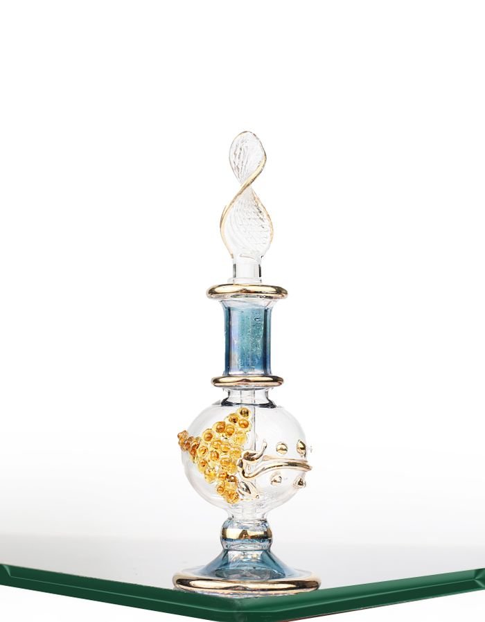 Artistic glass perfume bottle with intricate design on display table.